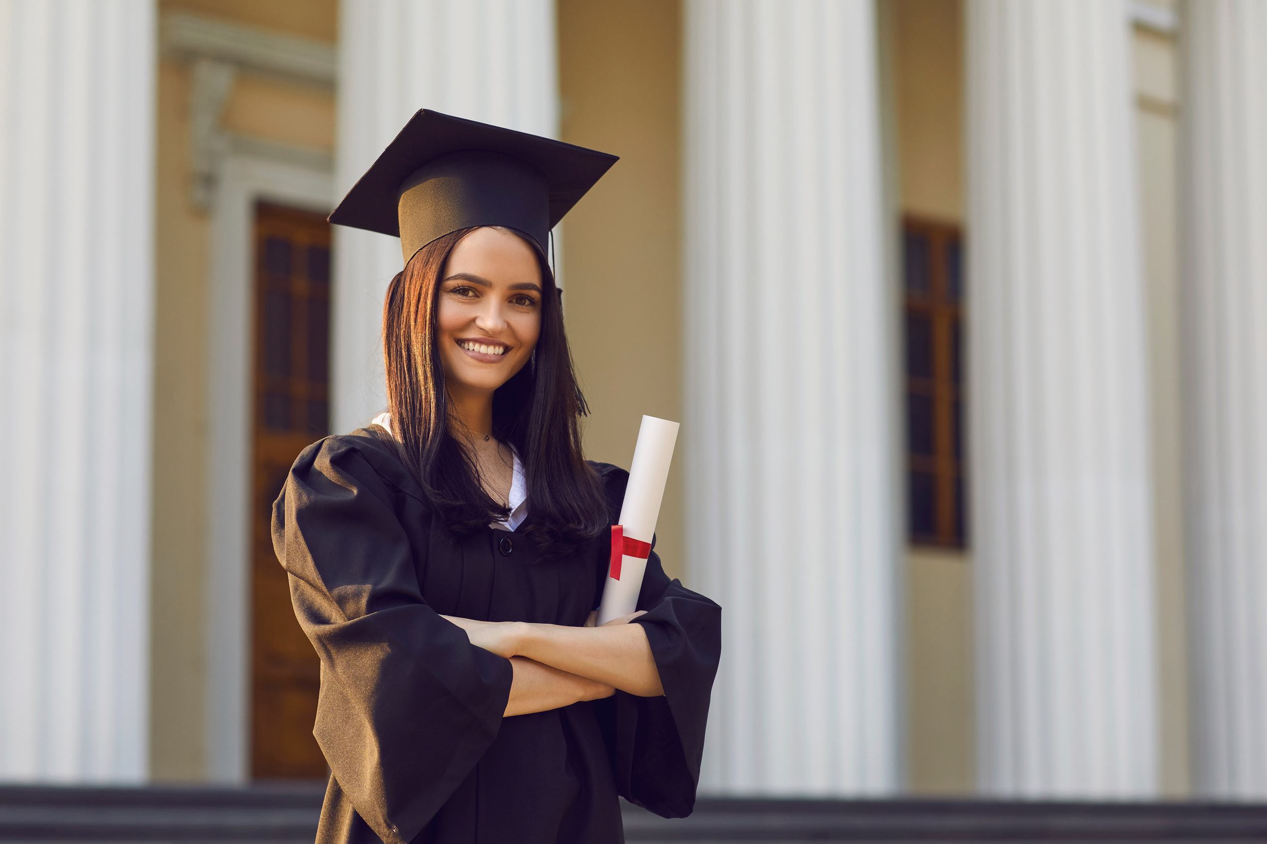 Portrait of Confident Female Student with Diploma in Hands on University Background.